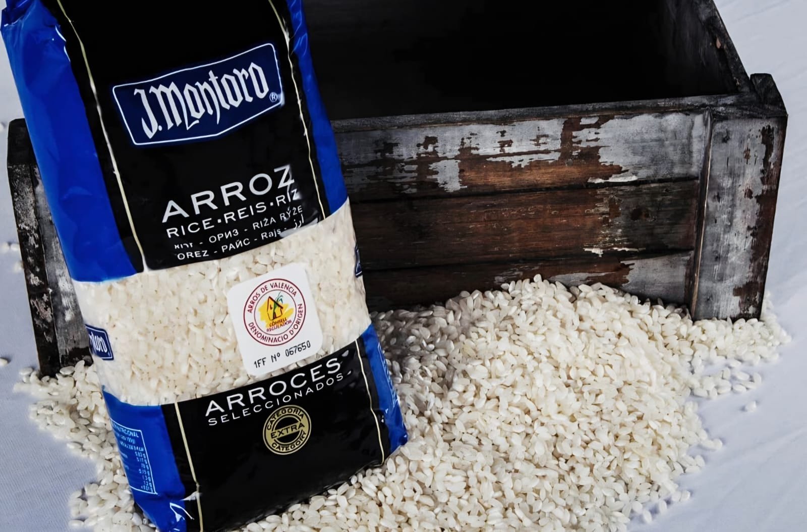 Paquete azul de arroz redondo extra J. Montoro junto a granos de arroz